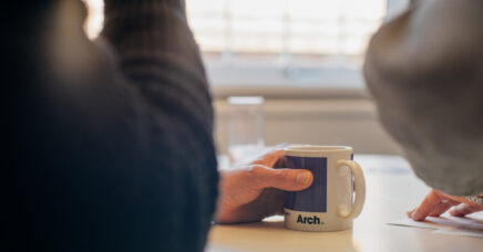 An Arch branded mug at a conference table