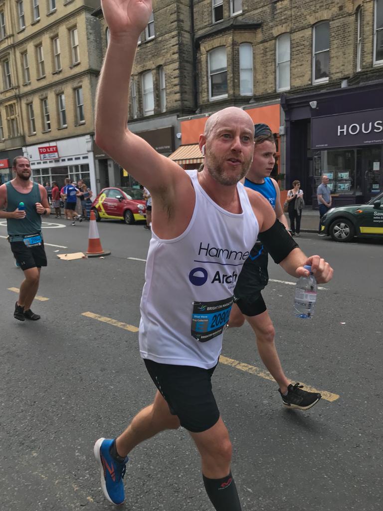 Runner waving while running in the 2021 Brighton Marathon