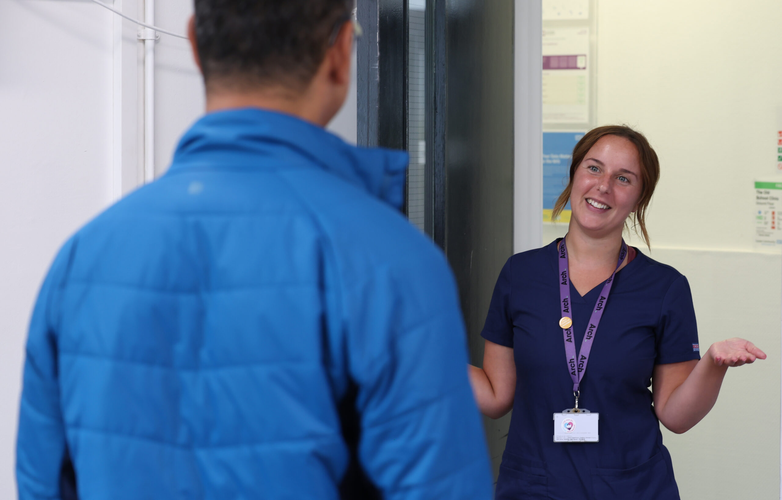 Arch nurse welcoming a patient from a door way, smiling